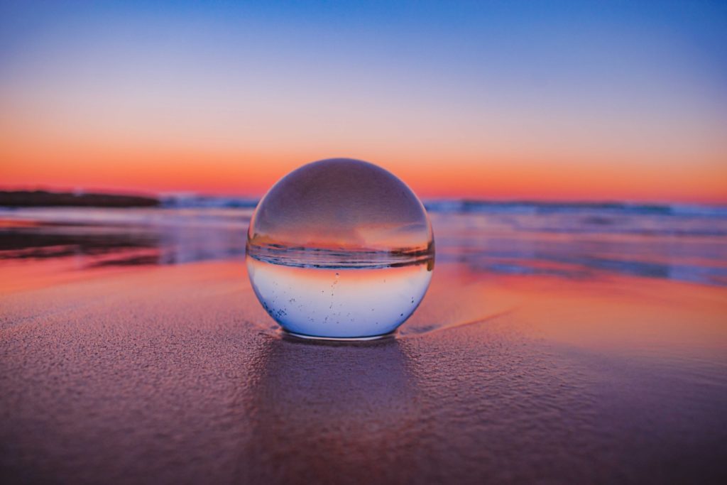 clear glass ball on gray sand during sunset